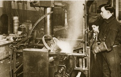Produzione di denaro: abbassamento di una pentola di metallo liquido in una macchina da English Photographer